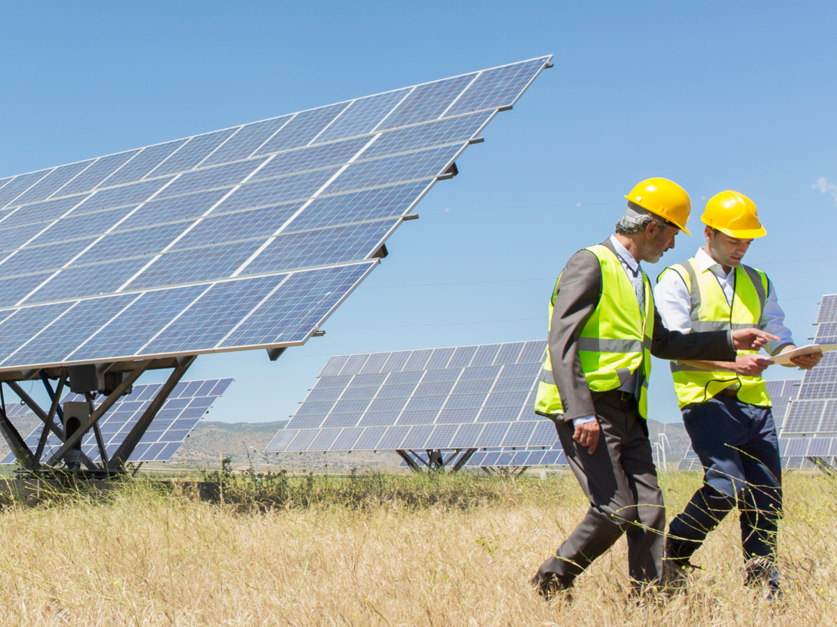 Workers reviewing an engineering report, with solar panels behind them