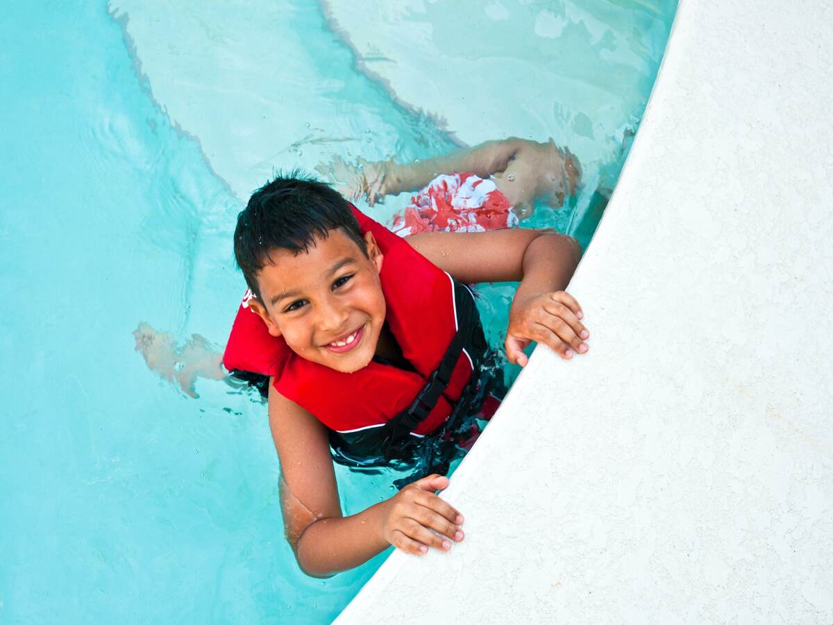 Smiling boy wearing lifejacket in swimming pool