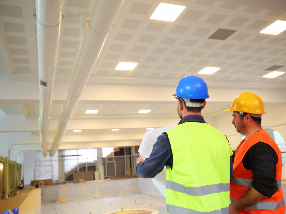 Construction workers looking at blueprints inside construction site.