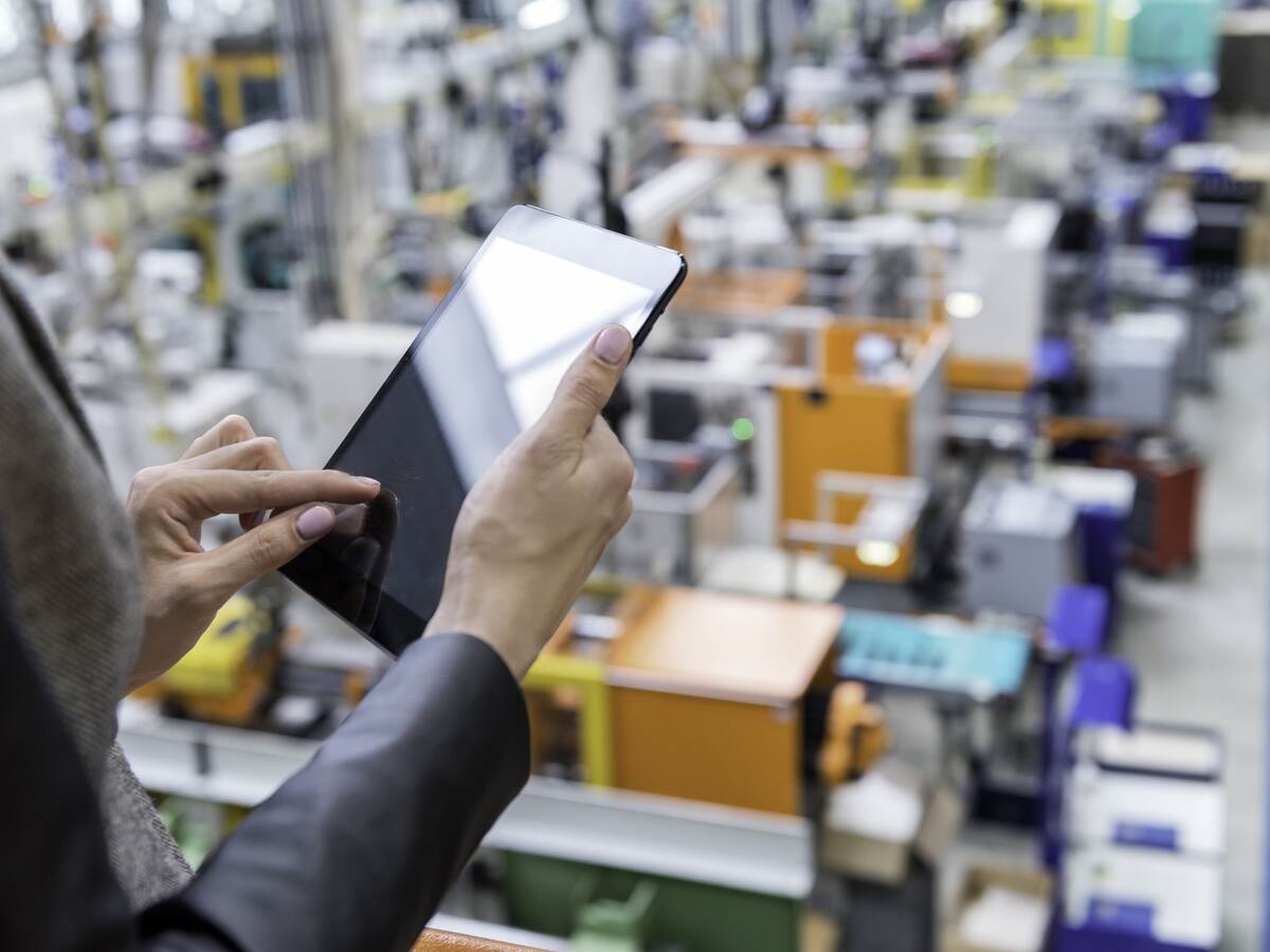 Manager reviewing a tablet while overlooking a factory floor