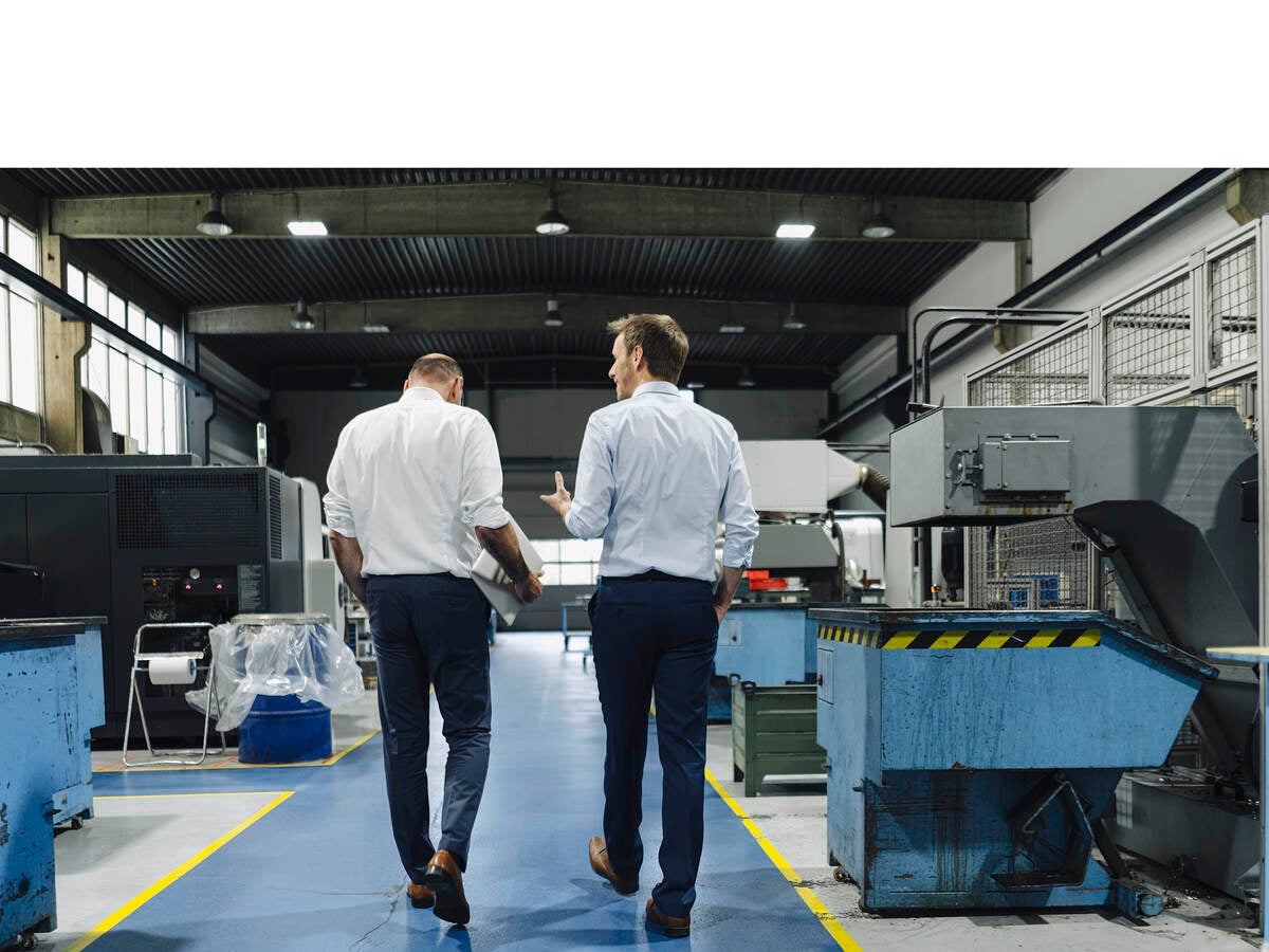 Two men walking and talking in a factory