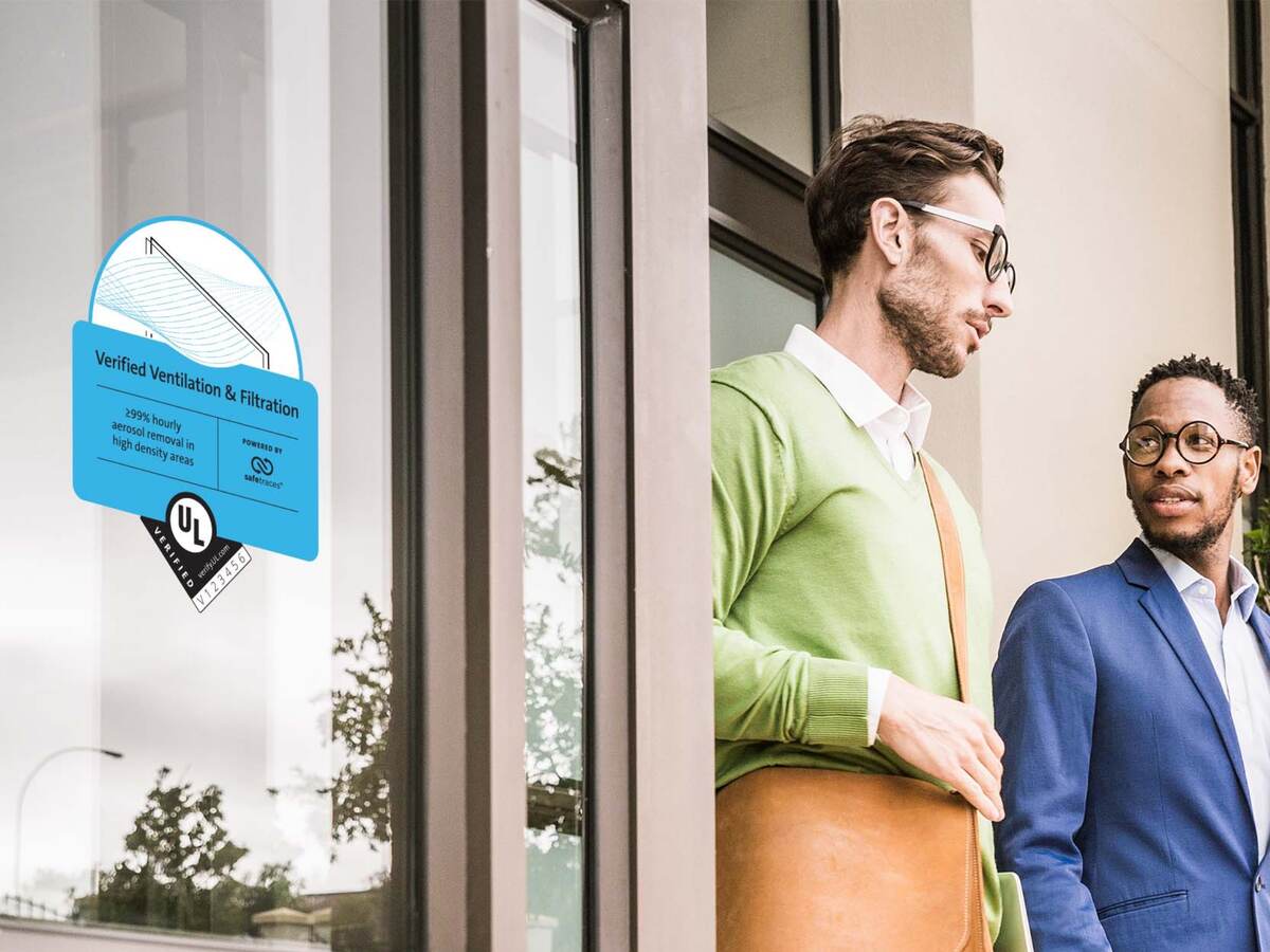 People talking outside of a building that has the Verified Ventilation and Filtration Mark