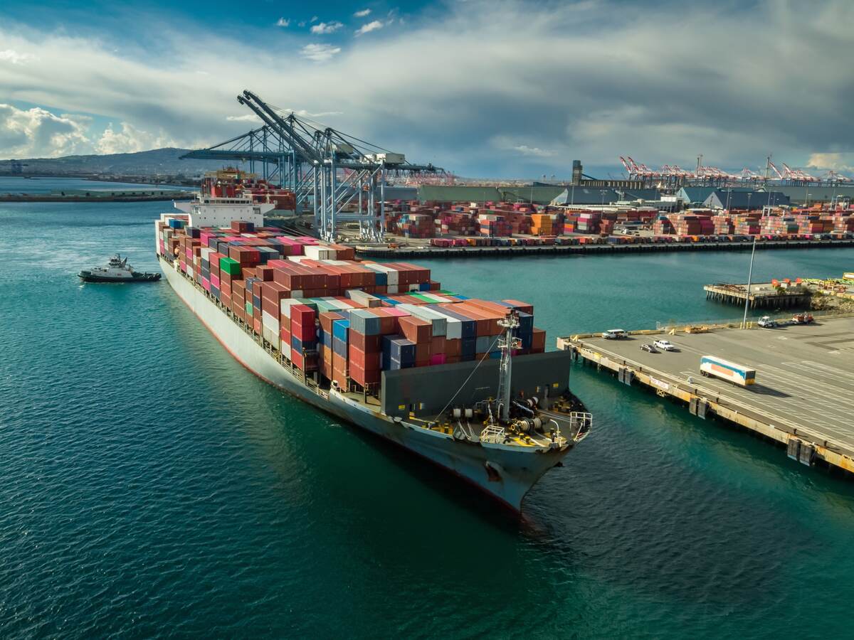 Tugboat maneuvering cargo ship at Dockside in Port of Long Beach.