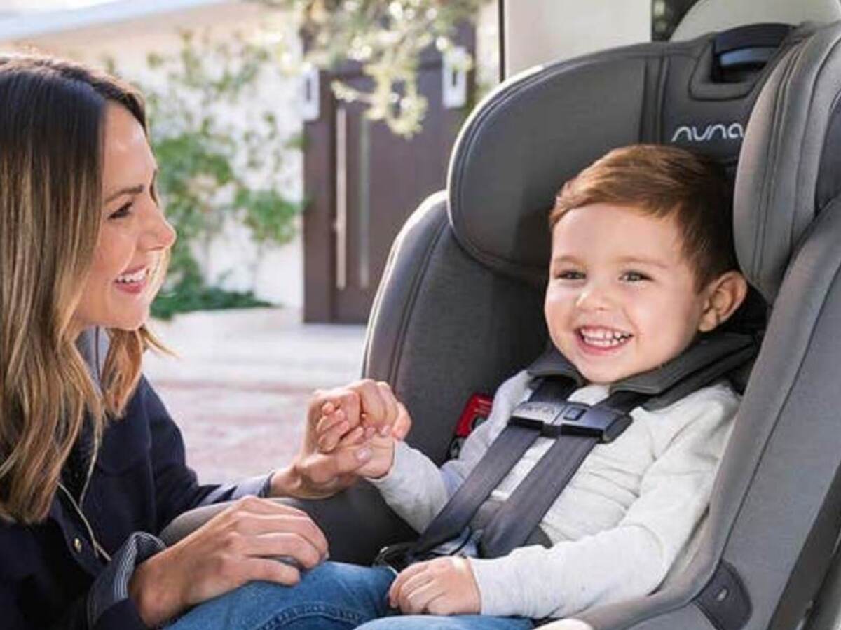small child in car seat holding womans hand