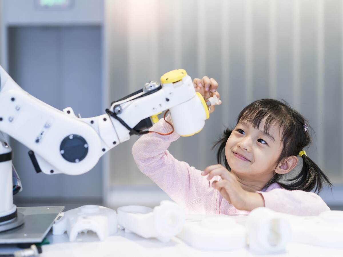 A young girl looking at a robotic arm.