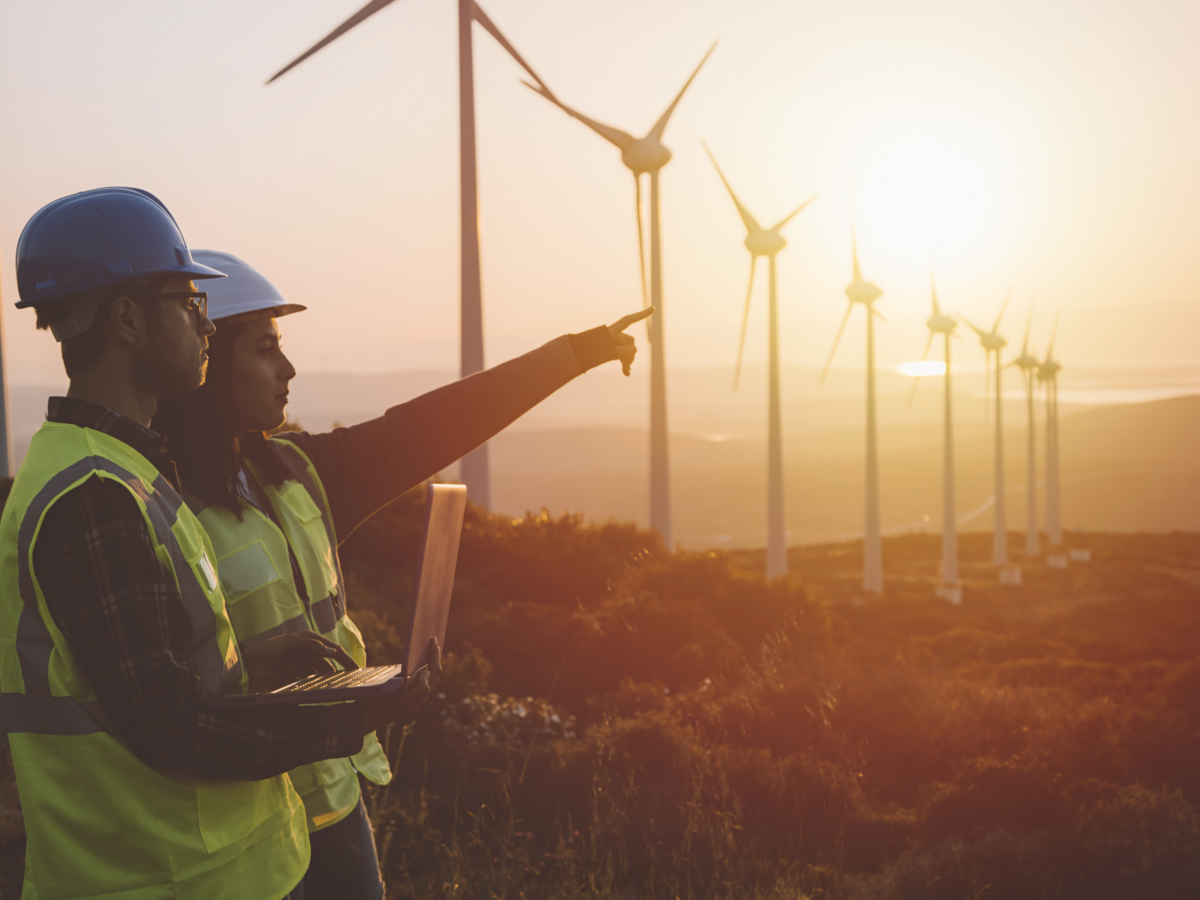 Maintenance engineer team working in wind turbine farm at sunset