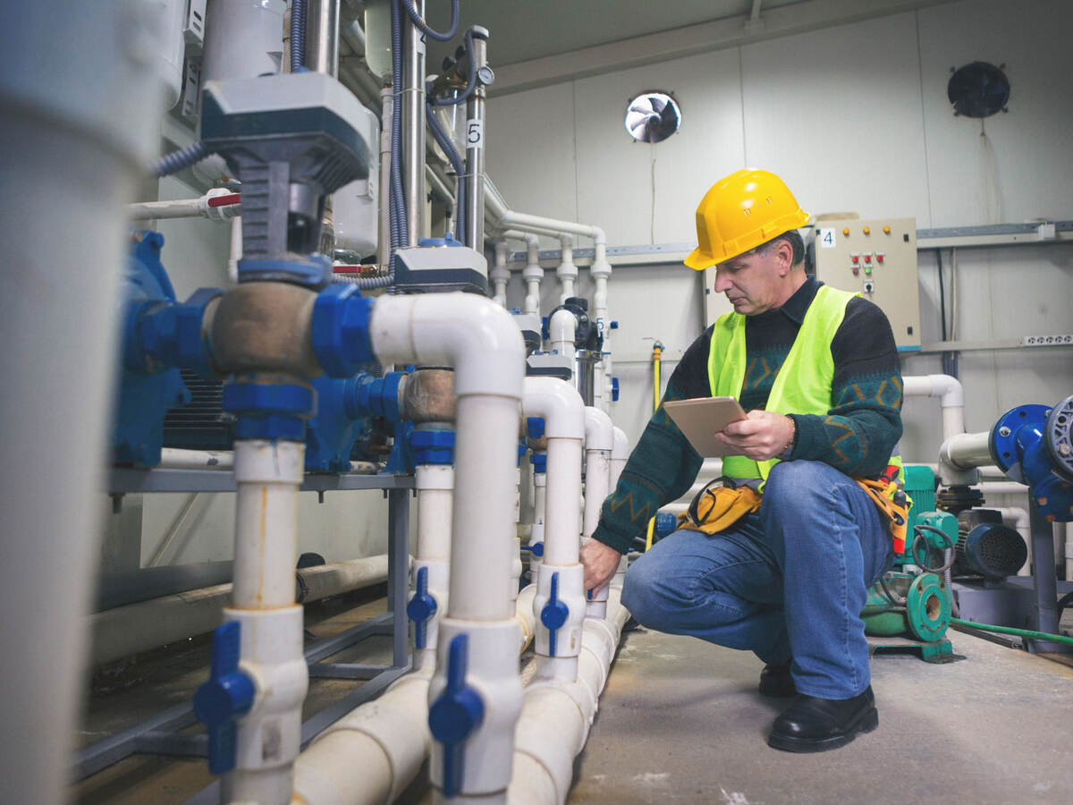 Senior repairman in boiler room checking pipes