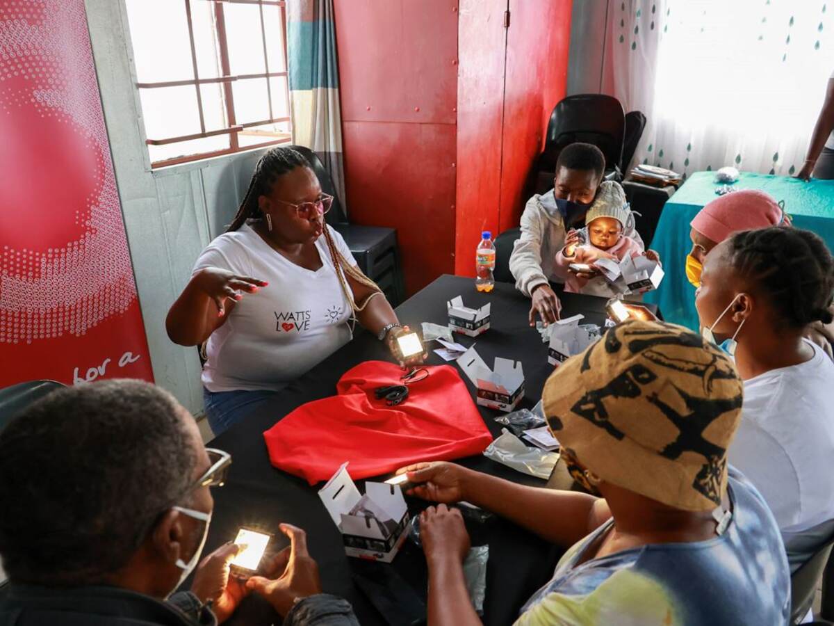 Group of South Africans sit at a table leaning how to use their Watts of Love solar-powered lights