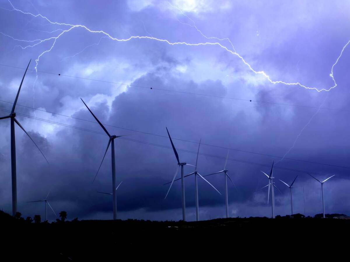 Lightning Over Wind Turbines Against Sky 