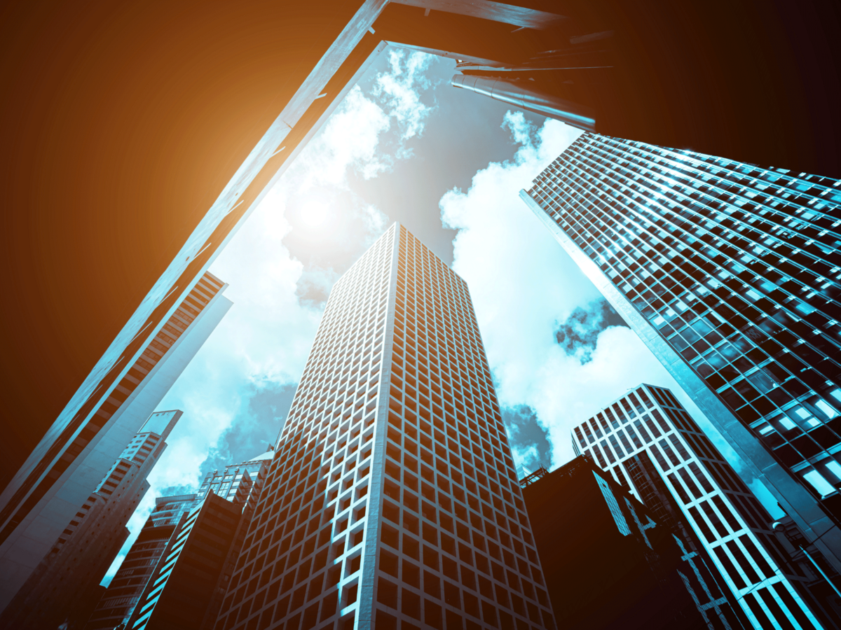 looking up through modern office buildings seeing sun streaming in