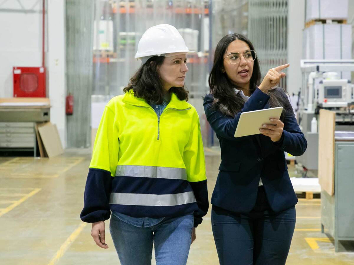 Female plant manager with tablet and middle-aged woman in hardhat