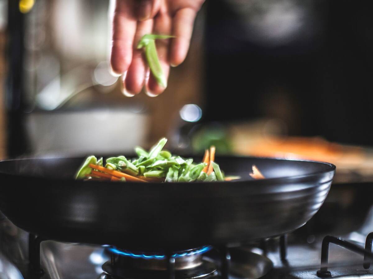 Sprinkling shredded vegetables in a pan for Korean pancakes.