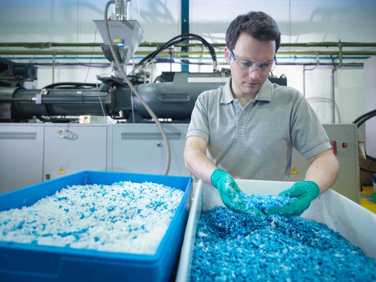 Worker inspecting recycled plastic in plastics factory