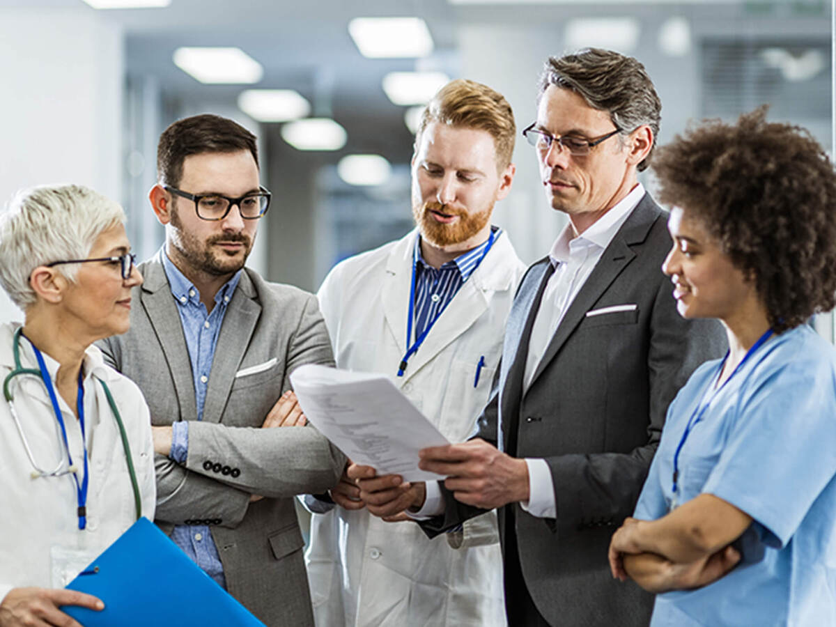 A group of five work co-workers review professional document in a medical setting