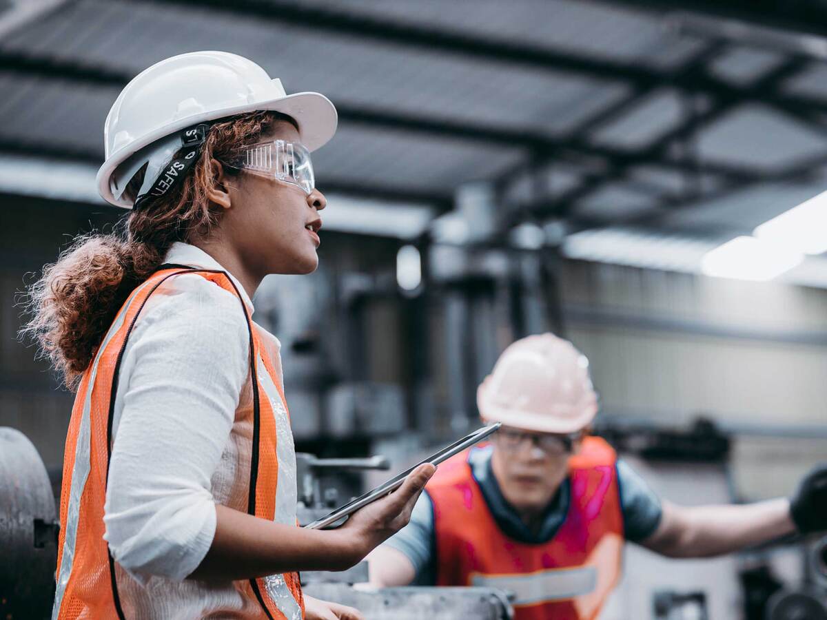 Female engineer wearing a helmet while standing in a factory 