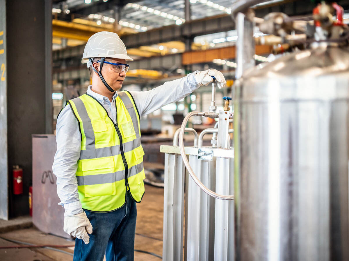 Worker operating a gas tank in a factory.  