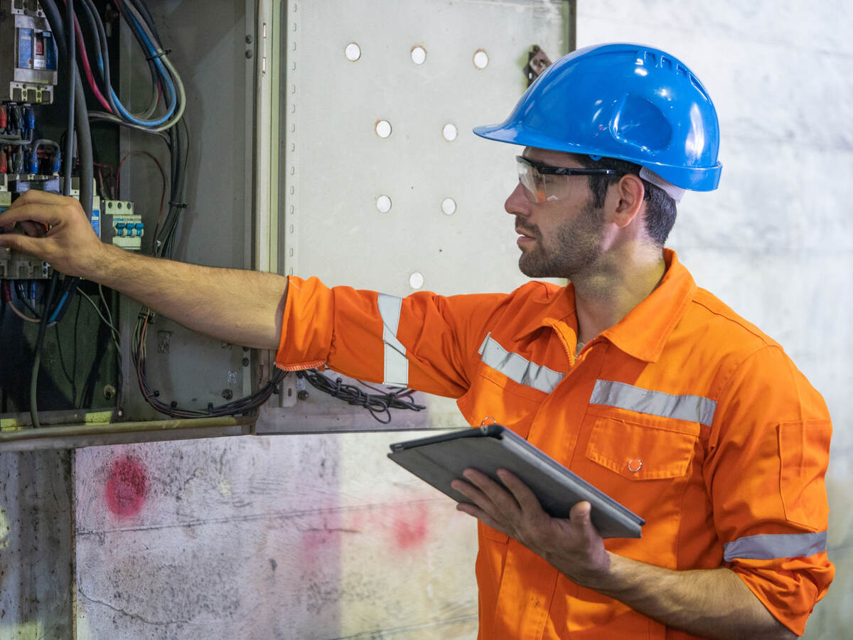 An electrician working at a circuit electrical panel.