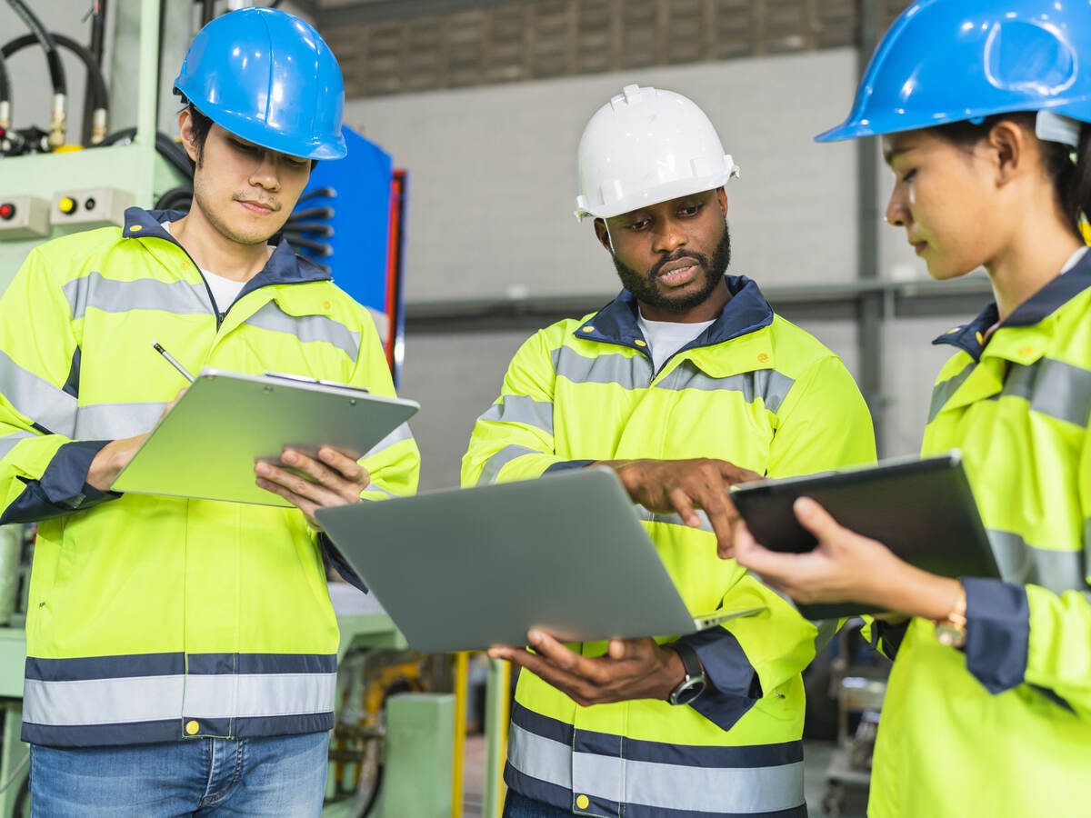 Workers in PPE holding clipboards and talking