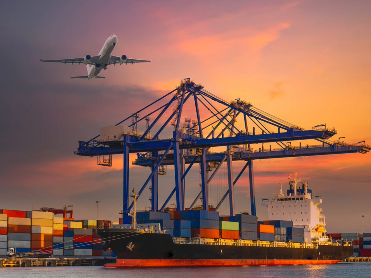 Cargo ship at a port with cargo containers with airplane overhead