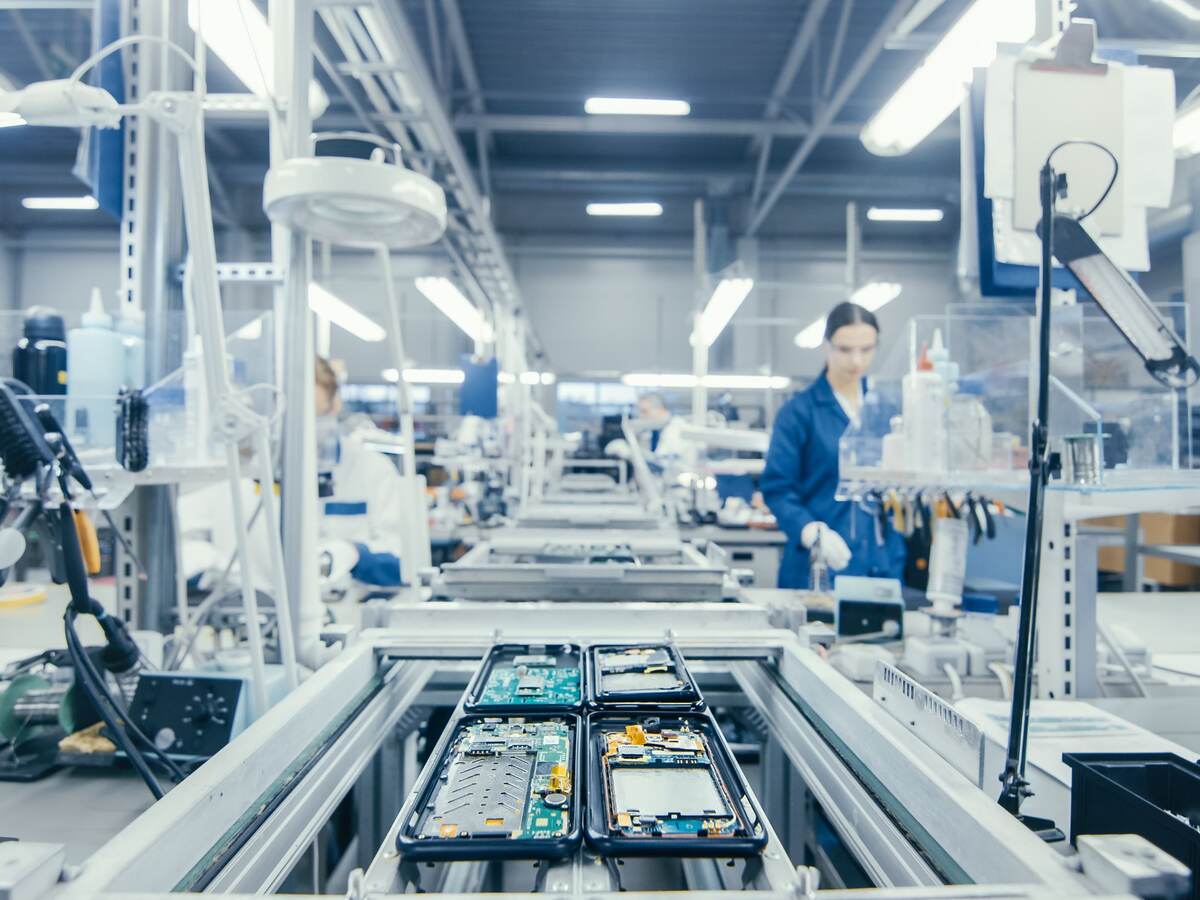 Shot of an Electronics Factory Workers Assembling Circuit Boards by Hand While it Stands on the Assembly Line. High Tech Factory Facility.