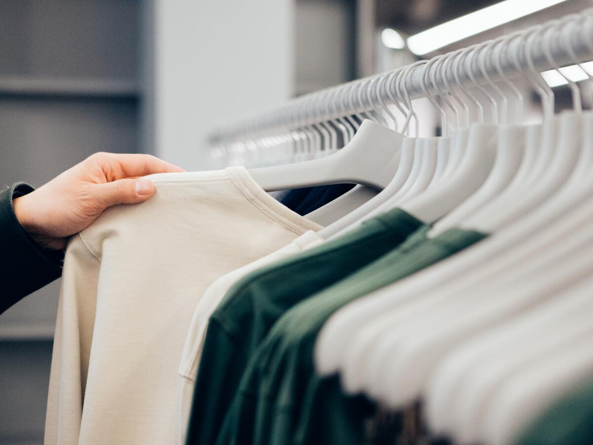 Cropped hand of man holding shirt in shop.