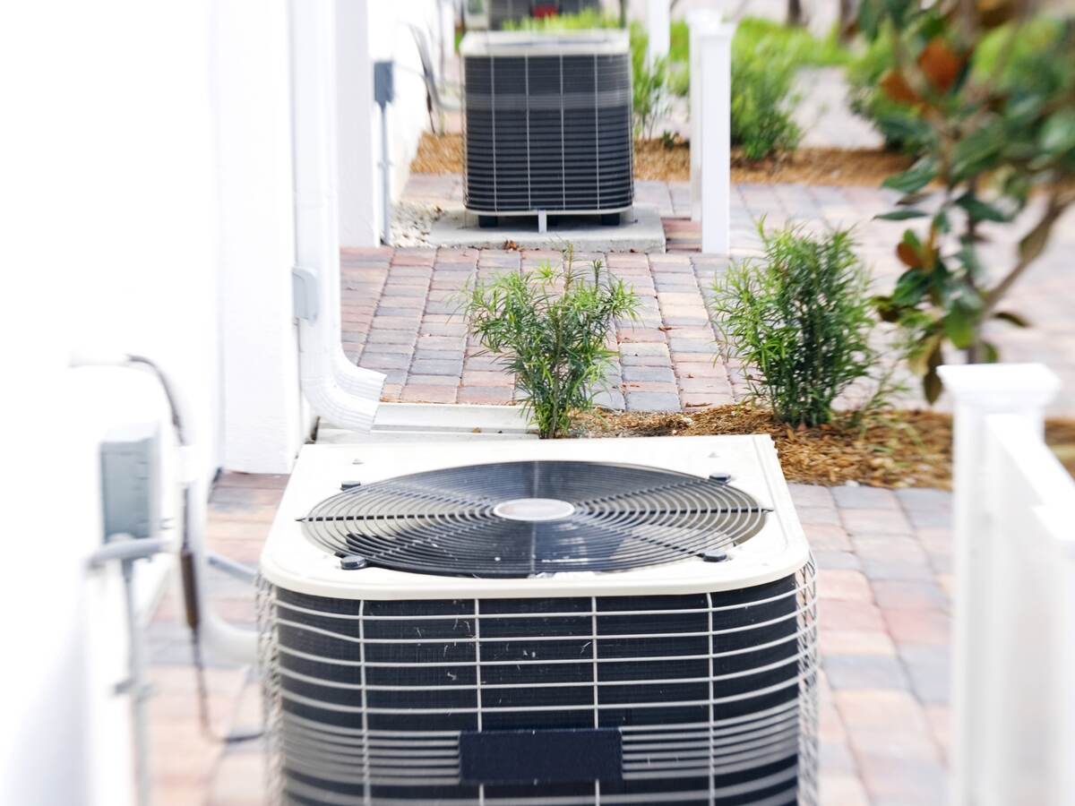 Row of air conditioning units on brick driveways.