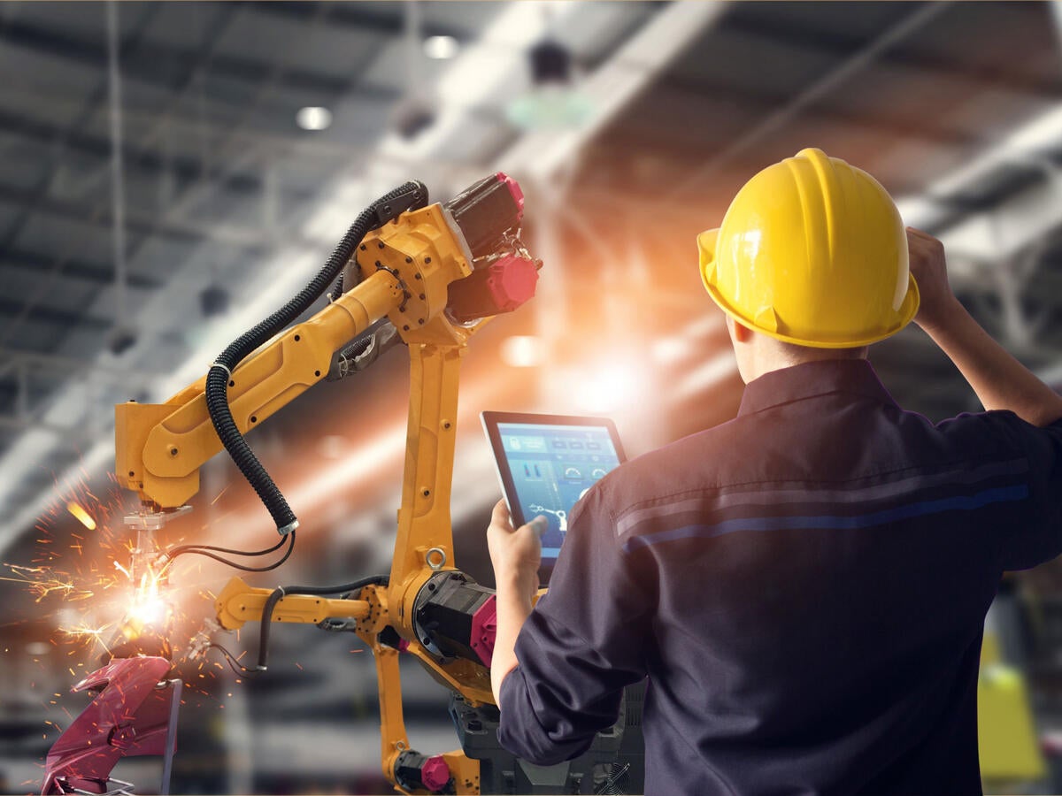 Worker overseeing automated machines in warehouse 