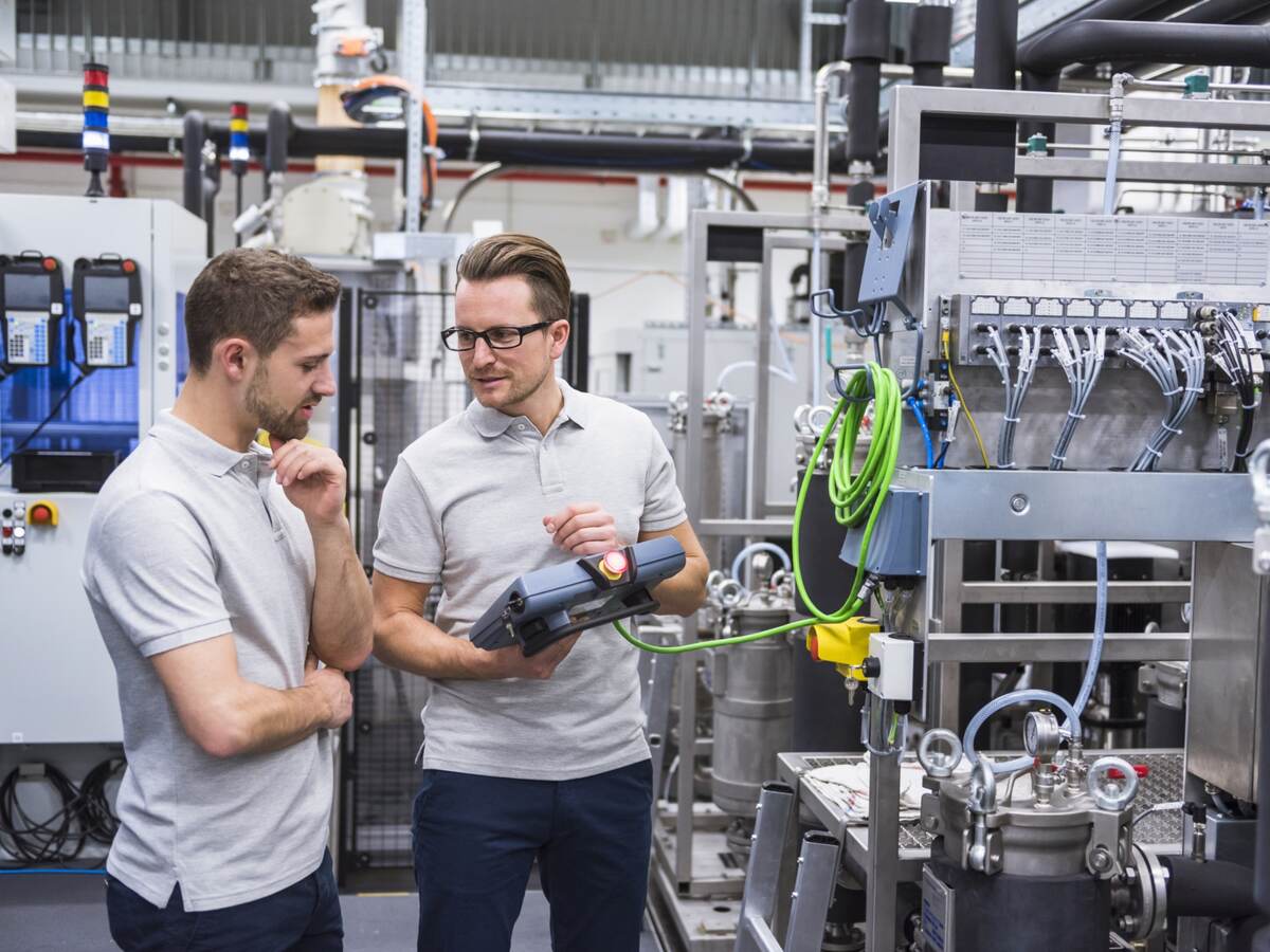 Two men with a control system on factory shop floor.