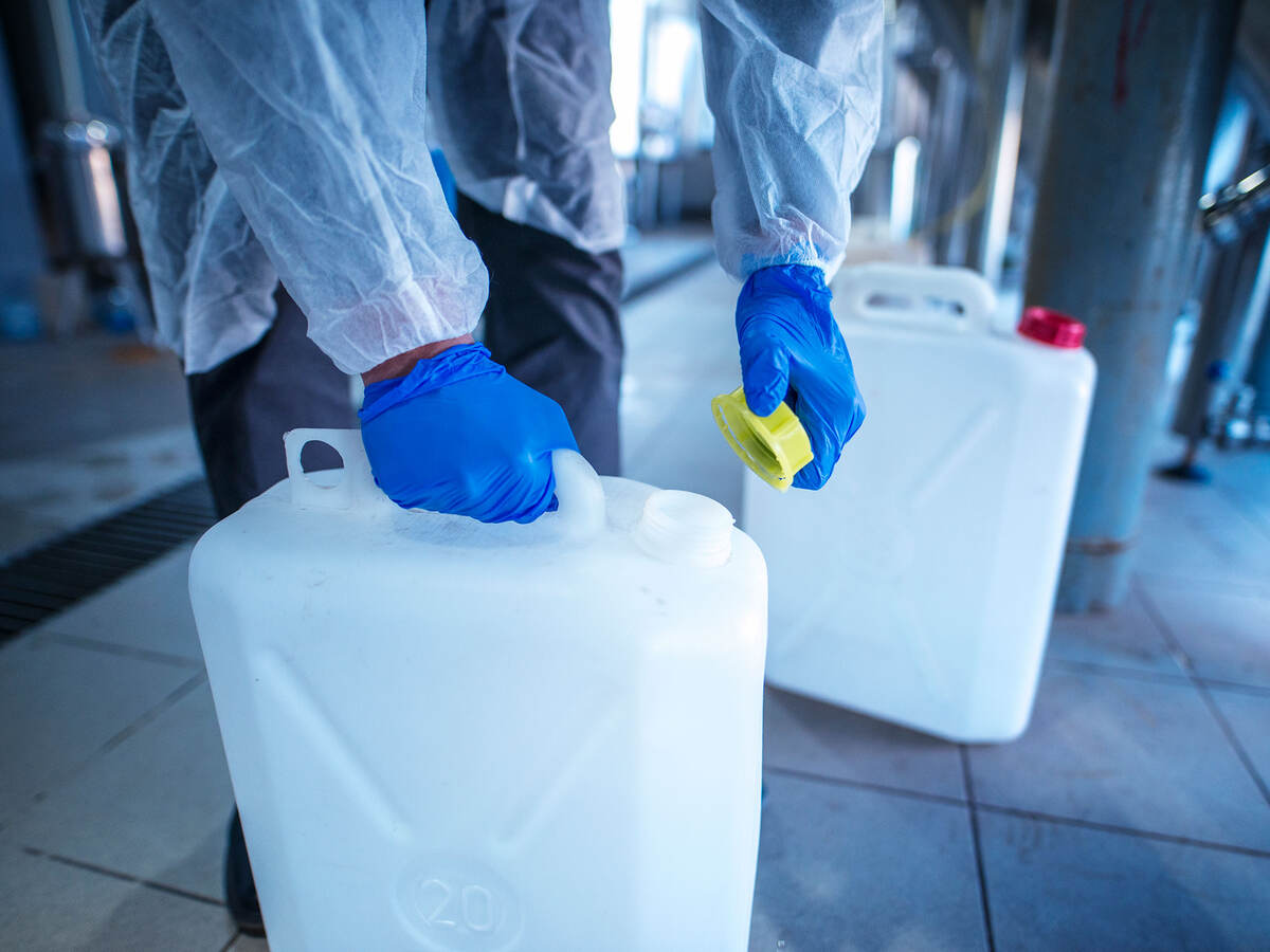 working with chemicals - person putting a yellow cap on a plastic chemical container