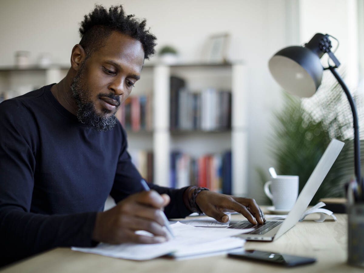 Person writing notes while sitting at a desk