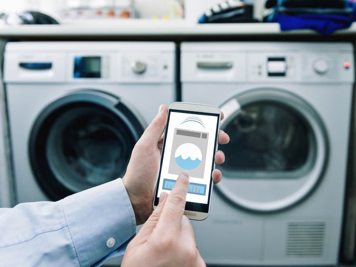 Consumer using mobile phone app to control washing machine.