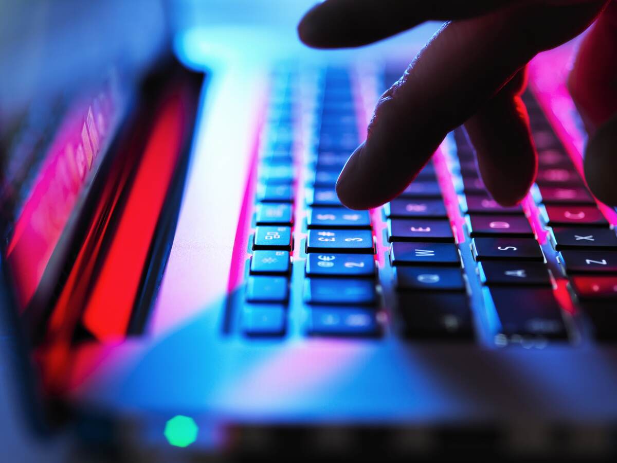 Man typing at his laptop computer at night.