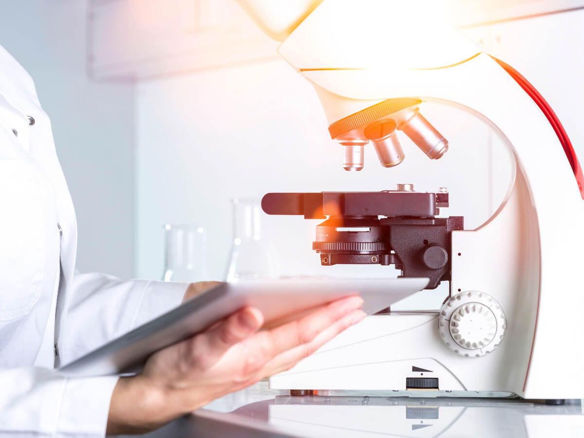 Scientist reviewing notes next to a microscope