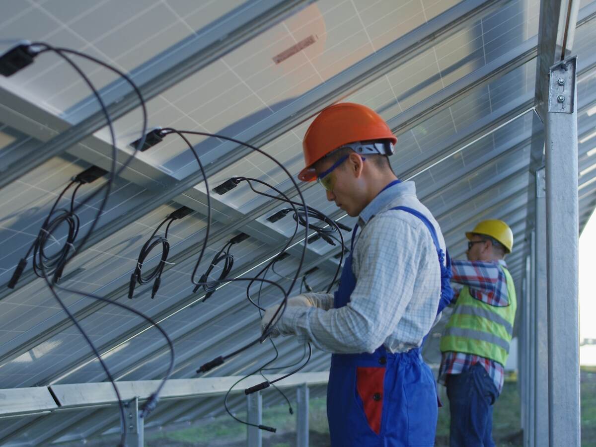 Workers connecting wires of solar panels