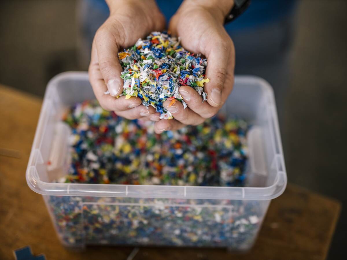 Man with container holding recycled plastic in factory