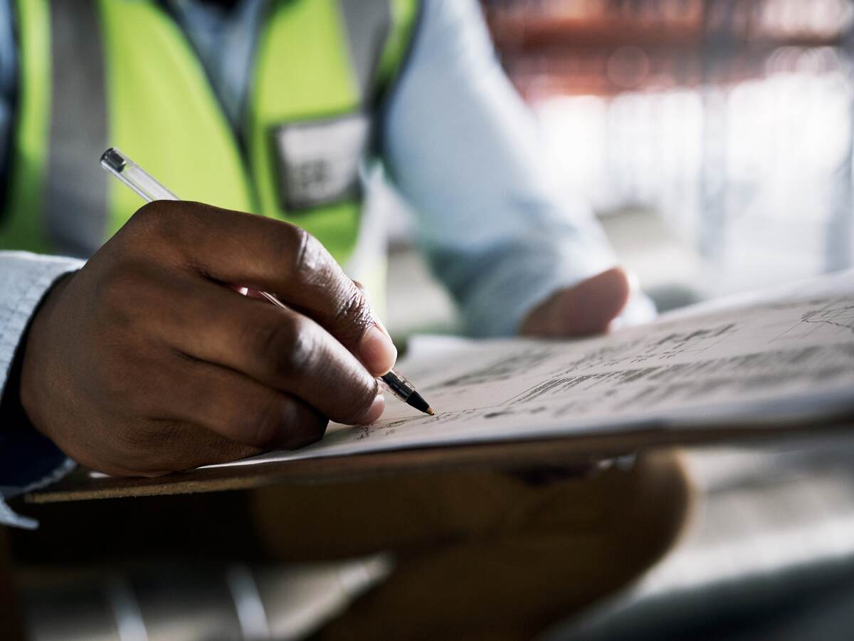 Shot of an unrecognisable builder filling out paperwork at a construction site