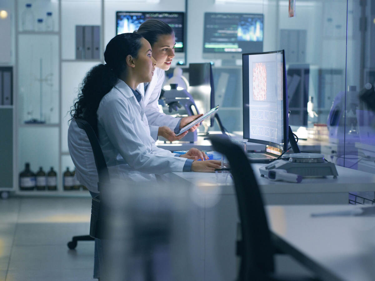 Two scientists in the lab viewing data on a laptop