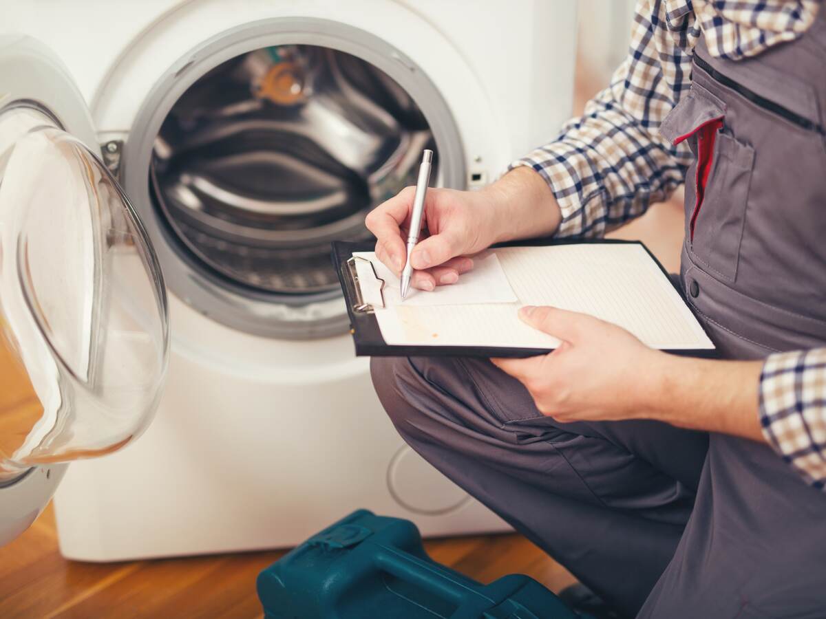 Repairman is repairing a washing machine.