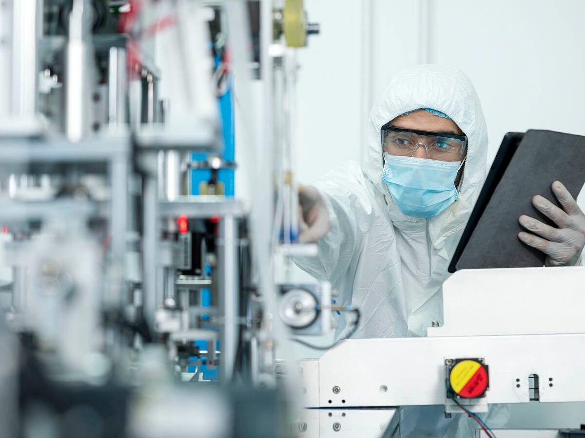 Shot of Caucasian Engineers using digital tablet for inspection quality of producing protective face mask in automated production line.