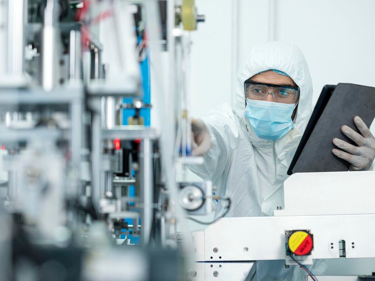 Shot of Caucasian Engineers using digital tablet for inspection quality of producing protective face mask in automated production line.