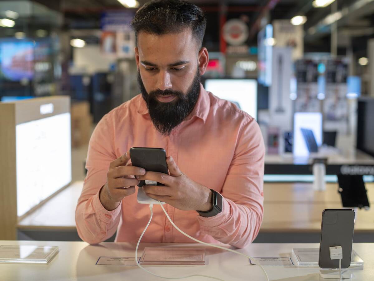 Young man testing out a mobile phone.