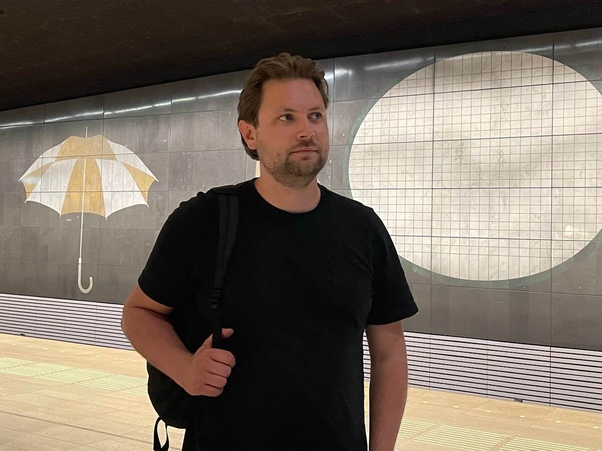 Bart Reuvenkamp stands in front of mural in black t-shirt. 