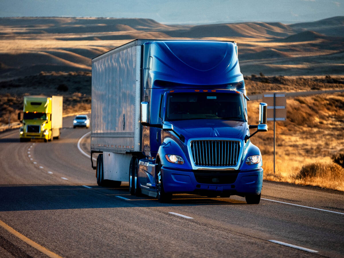 A semi truck driving down a highway at dusk