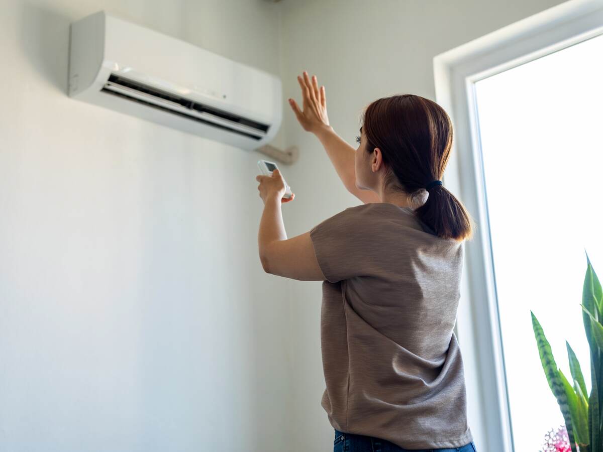Woman turning on air conditioner.