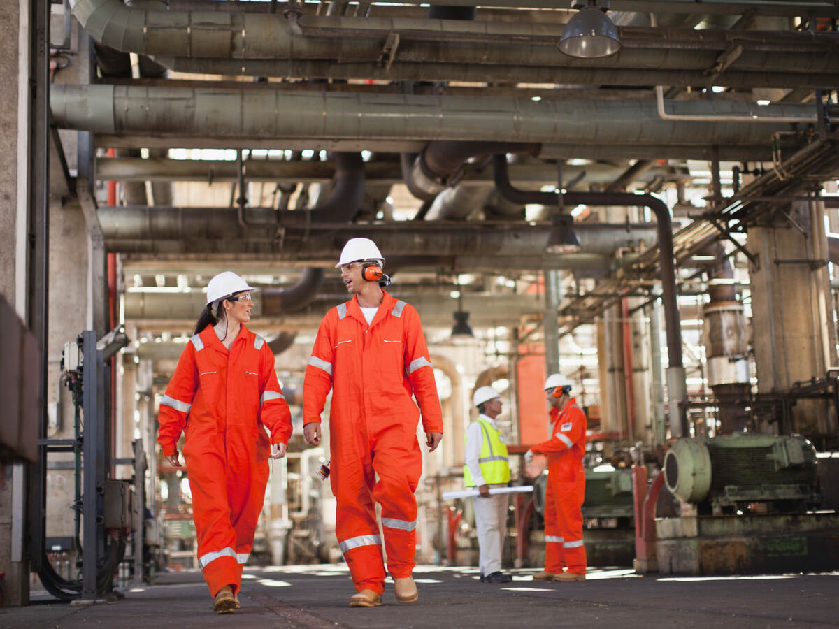 Workers wearing PPE and walking at oil refinery