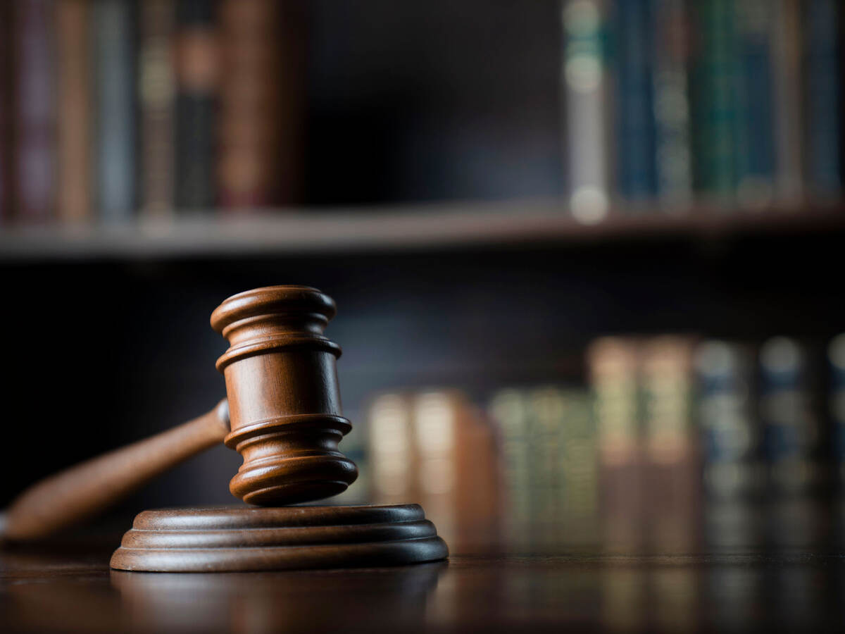 A judge's gavel on a wooden desk with books in the background