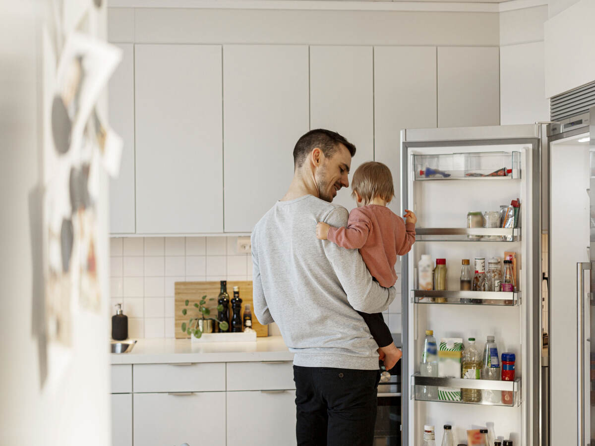 Father holding a child and opening a refrigerator door