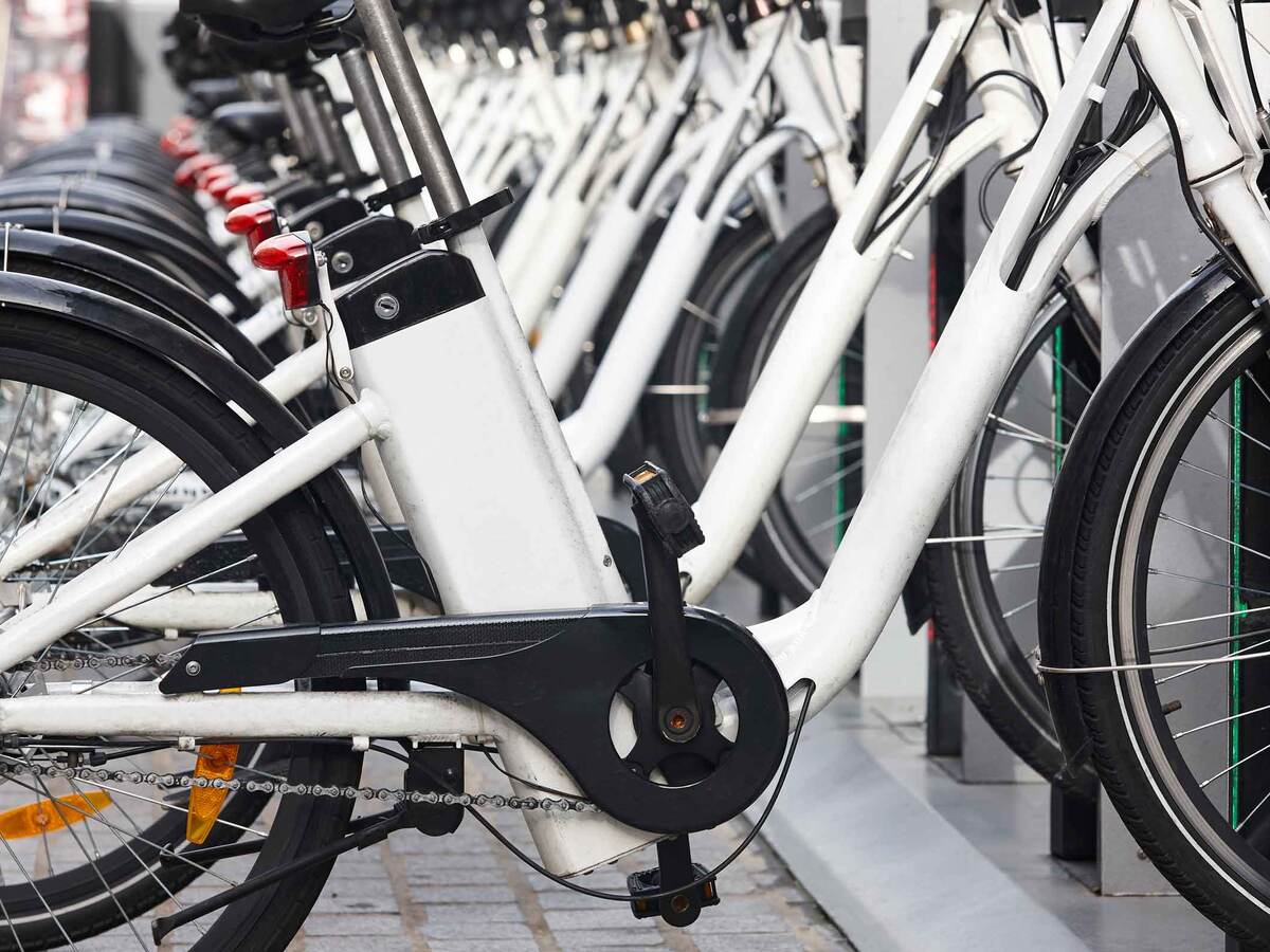 Row of white electric bikes lined up on a bike rack