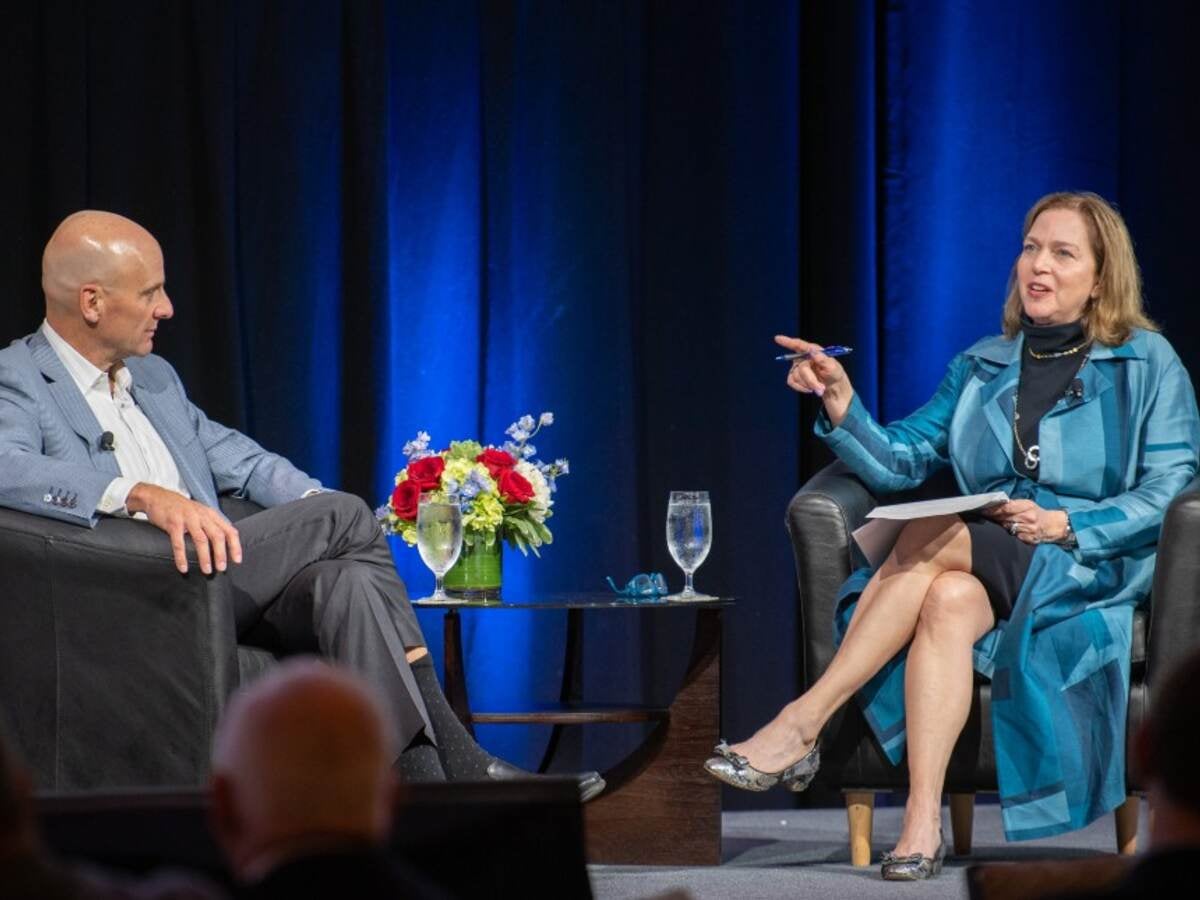 Jenny Scanlon talking while seated on main stage in blue dress. 