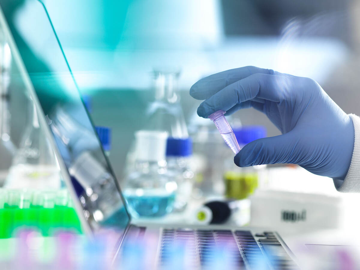 A scientist's gloved hand holding a vial